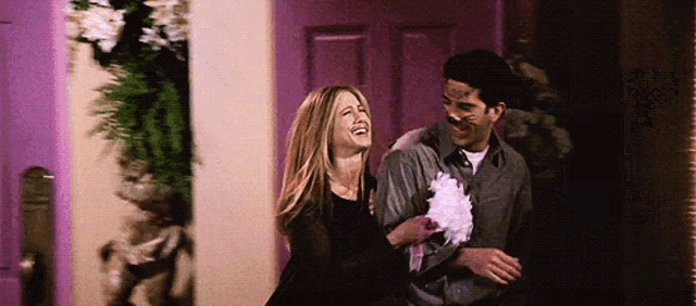 a man and a woman are laughing while holding cotton candy .