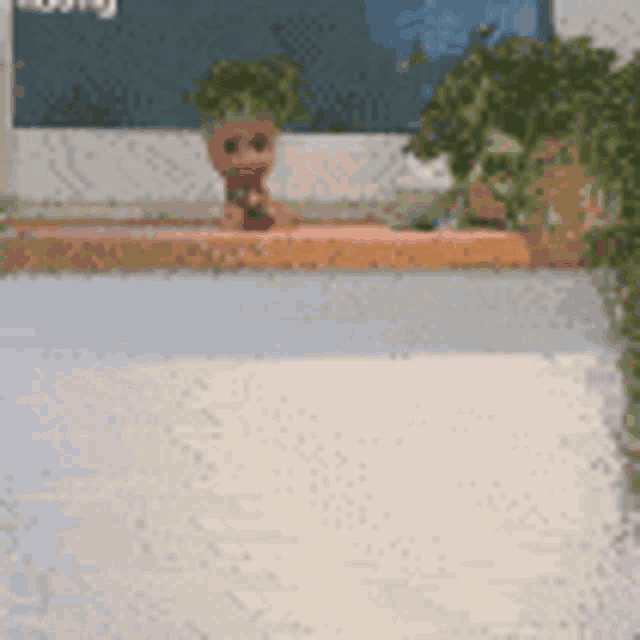 a baby groot figurine is sitting on a table next to a computer monitor .