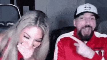 a man and a woman are laughing together while sitting next to each other .