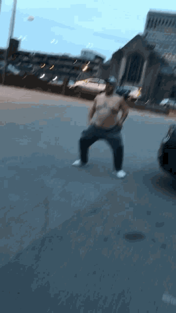 a shirtless man is dancing on the street in front of a parking garage