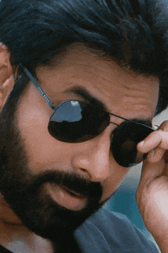 a man with a beard is wearing sunglasses and adjusting his lens