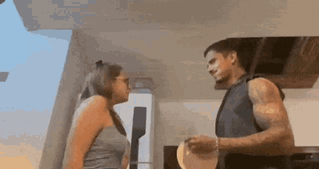a man and woman are standing next to each other in a kitchen .