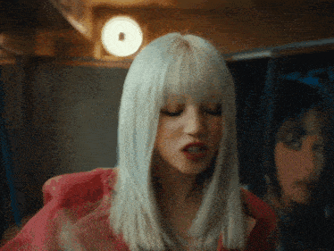 a woman with blonde hair and red lips is standing in front of a mirror