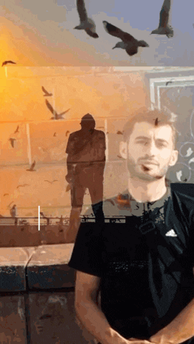 a man in a black adidas shirt is standing in front of a statue