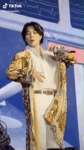 a man is standing on a stage with a microphone in his hand and holding his stomach .