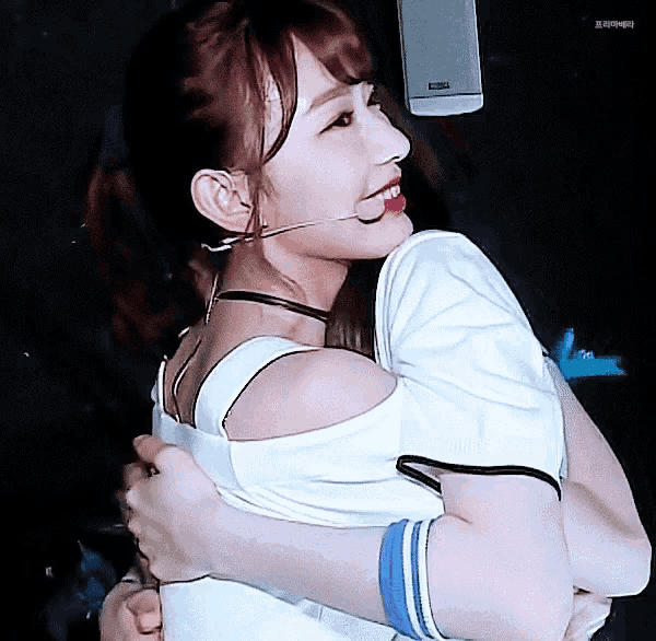 a woman wearing a microphone is hugging someone
