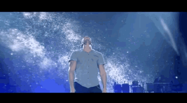 a man singing into a microphone on a stage in front of a blue background