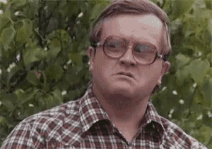 a man wearing glasses and a plaid shirt is looking at the camera .