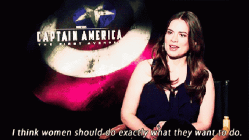 a woman is sitting in front of a captain america poster