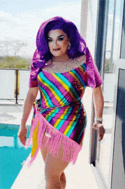 a woman with purple hair and a colorful dress is standing next to a window
