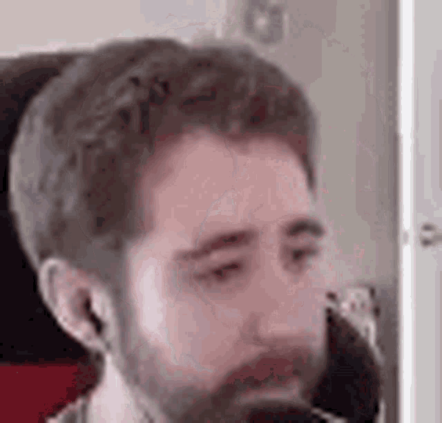 a man with a beard and ear buds is sitting in front of a computer monitor .
