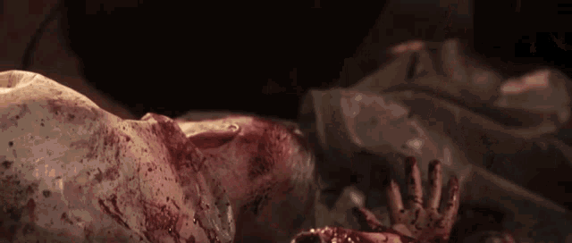 a person laying on the ground with blood on their face and hands