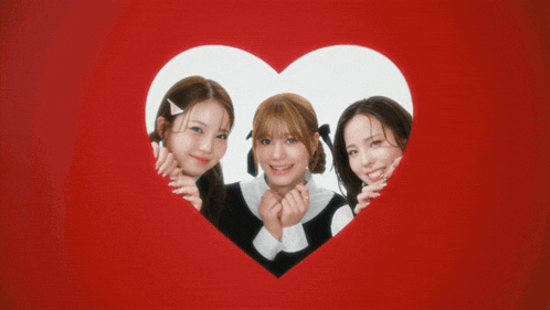 three girls are posing in front of a heart shaped frame