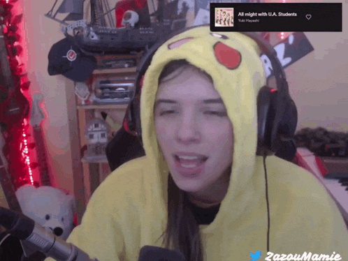 a woman wearing headphones and a pikachu hoodie singing into a microphone