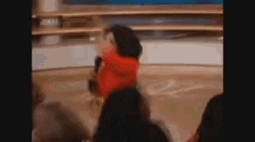 a woman in a red jacket is dancing in front of a crowd with a sign that says 2004 in the background