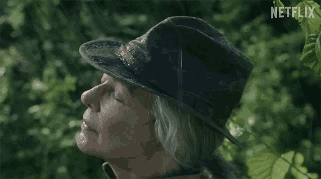 a woman wearing a hat with netflix written on the bottom of the screen