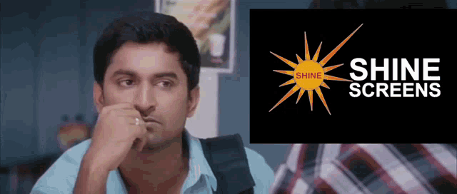 a man sitting in front of a shine screens sign