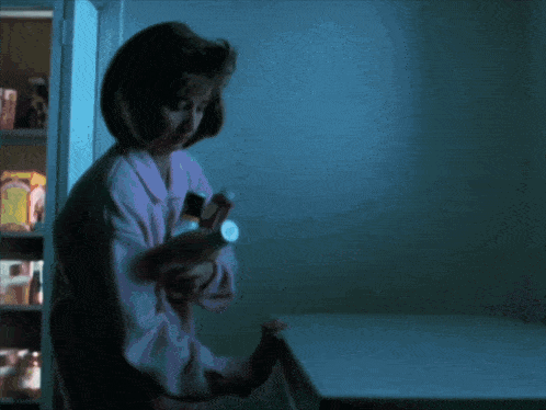 a woman holding a flashlight in front of a fridge
