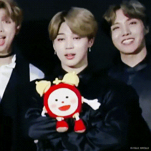 a group of young men are standing next to each other holding a stuffed animal .