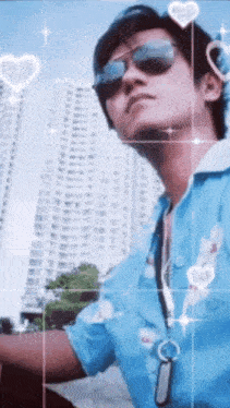 a man wearing sunglasses and a blue shirt stands in front of a skyscraper
