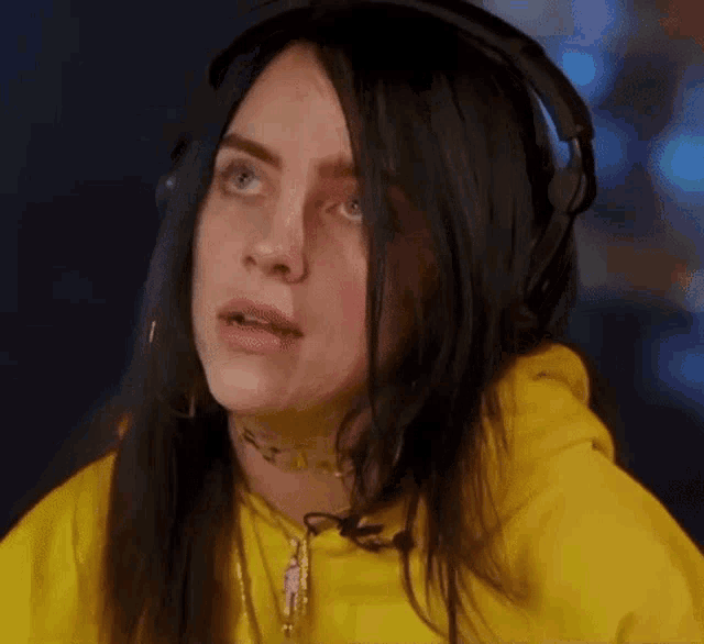 a close up of a woman wearing headphones and a yellow hoodie