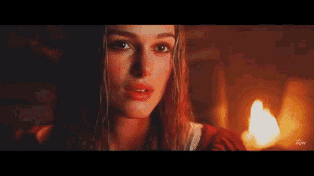 a woman is standing in front of a fireplace in a dark room .
