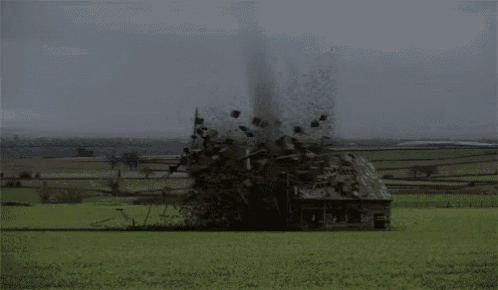 a large explosion in a field with a lot of pieces flying in the air