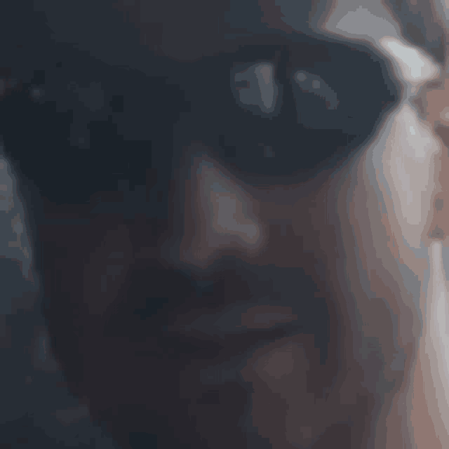 a close up of a man 's face wearing sunglasses and a hat .