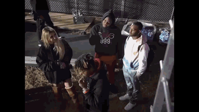 a man wearing a 999 hoodie stands in a crowd