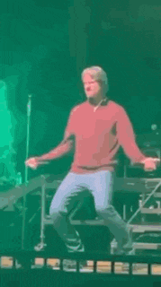 a man is dancing on a stage in front of a microphone .