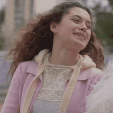 a woman in a pink jacket and sweater is smiling .