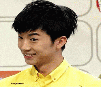 a young man wearing a yellow shirt is smiling and looking to the side .
