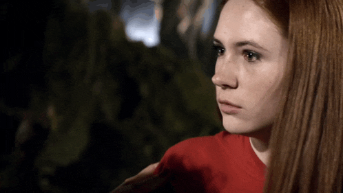 a close up of a woman 's face with red hair and a red shirt