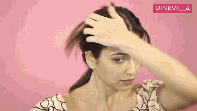 a woman is spraying her hair in front of a pink wall that says pinkvilla on it