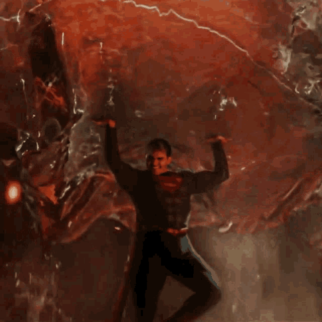 a man in a superman suit is standing in front of a red background