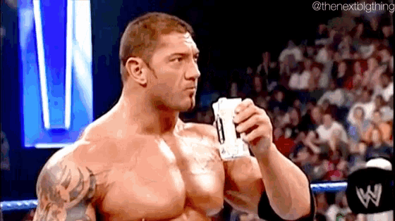 a muscular wrestler is holding a piece of paper in his hand .