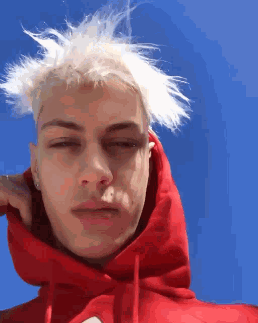 a young man wearing a red hoodie with white hair