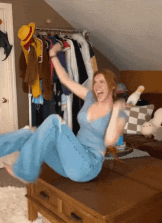 a woman in a blue shirt is sitting on a table with her arms in the air
