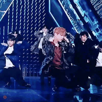 a group of men are dancing on a stage in front of a crowd .