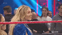 a woman is standing in a wrestling ring surrounded by people .