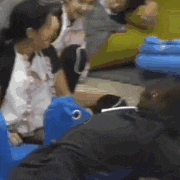 a group of people are sitting in blue chairs and talking .
