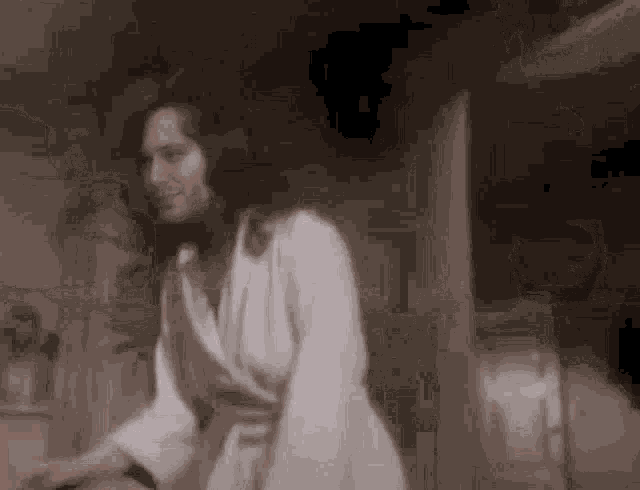 a woman in a white robe is standing in a room .