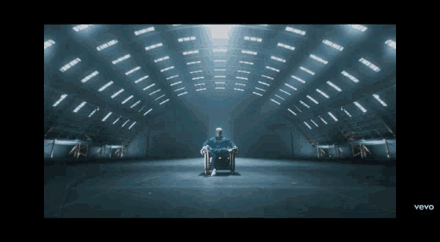 a man in a blue suit is sitting in a chair in a dark room with the words vevo on the bottom right