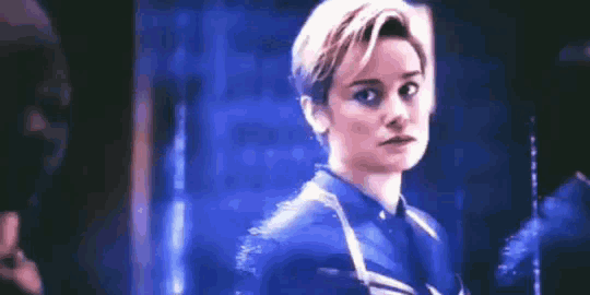 a woman in a blue suit is standing in a dark room .
