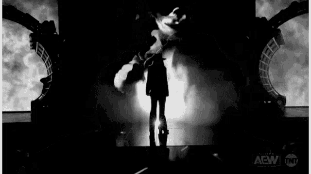 a black and white photo of a group of people standing on a stage in front of a large screen .