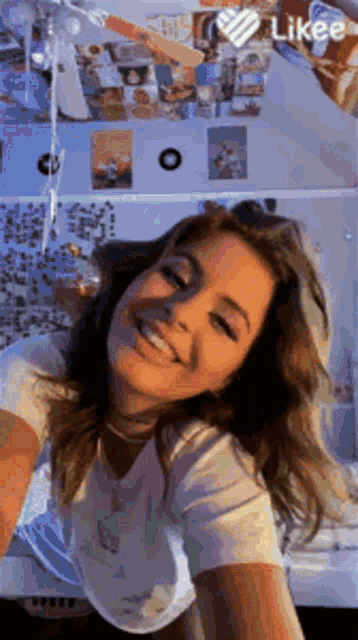 a girl is smiling and taking a selfie in front of a wall with posters on it .
