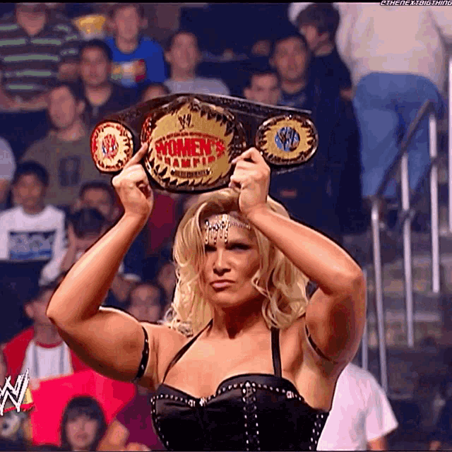a woman holding a women 's wrestling championship belt