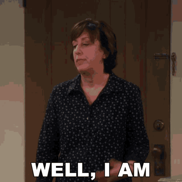 a woman in a polka dot shirt says well i am in front of a door
