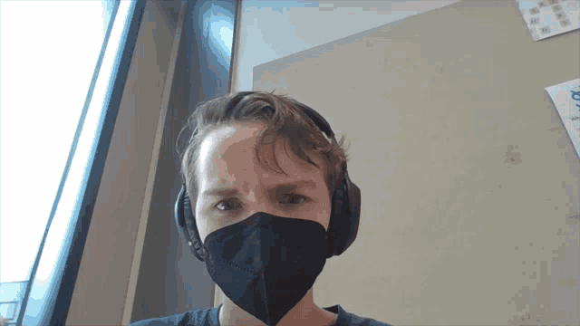 a man wearing headphones and a face mask looks at the camera