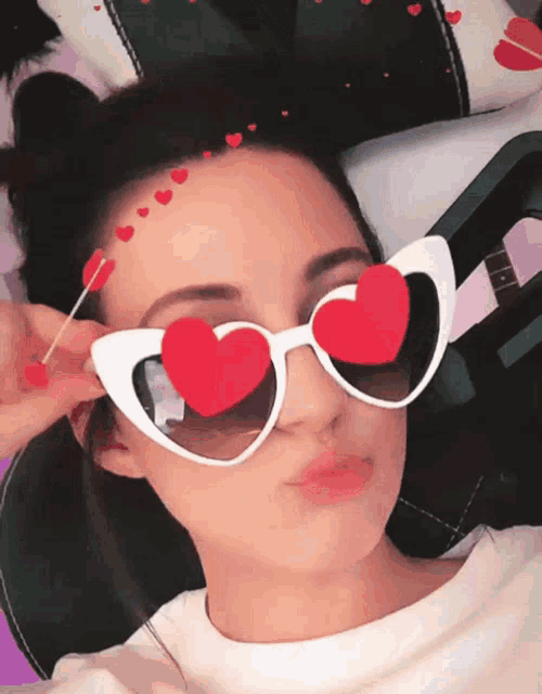 a woman wearing heart shaped sunglasses and a lollipop